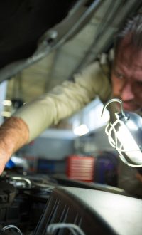 mechanic-examining-car-with-lamp