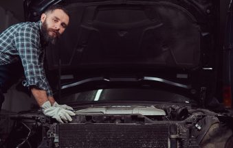 Mechanic man in uniform repairing car in the garage. Service station.